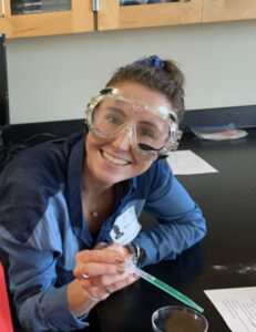 Smiling employee with pipette and safety glasses