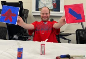 Smiling man showing his acrylic paintings