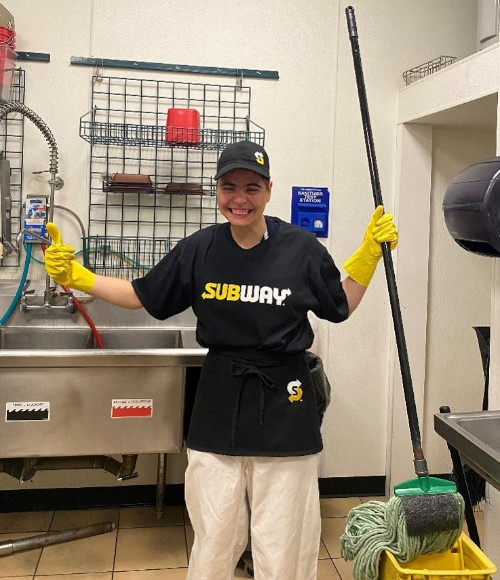 Transitions member working at Subway, smiling with two thumbs up